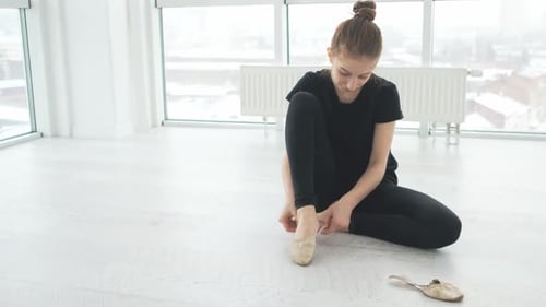 Woman Puts on Ballet Shoes in Studio
