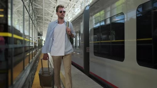 Man Walks on Train Platform with Rolling Suitcase