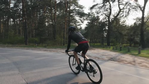 Confident strong triathlete pedaling on bicycle in the park