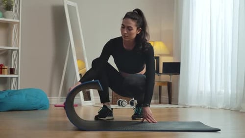 Confident Slim Caucasian Sportswoman Unrolling Exercise Mat at Home and Looking at Camera. Portrait