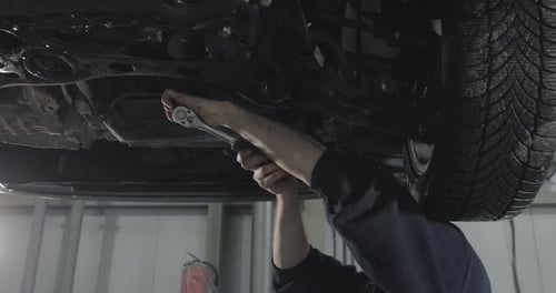 Mechanic Repairing Car Engine On The Lift. Close Up