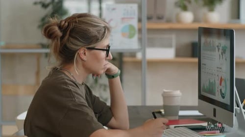 Businesswoman Analyzing Graphs on Computer in Office