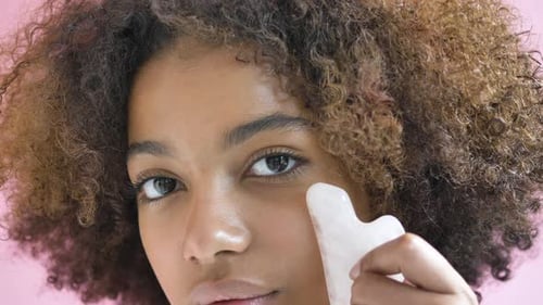 Young Adult Using Gua Sha Beauty Tool on Face