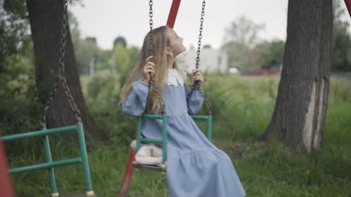 Charming Cute Girl Swinging on Swings Outdoors