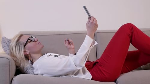 Woman Relaxes on Couch with Mobile Phone
