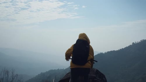 Successful woman hiker open arms on top of a mountain.