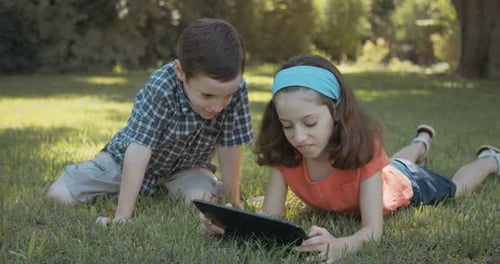 Children Enjoying Tablet Outdoors on Green Grass