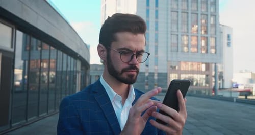 Man Uses Smartphone With Surprised Expression in City