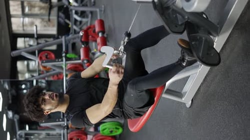 Determined Man Doing Cable Row Exercise at Gym