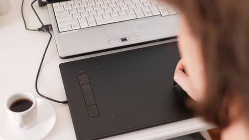Man Works at Computer on Graphics Tablet and Drinks Coffee