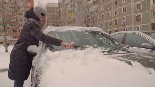 Adult Removing Snow From Car In Winter