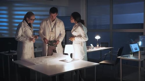 Engineers Collaborate Over Circuit Board at Night