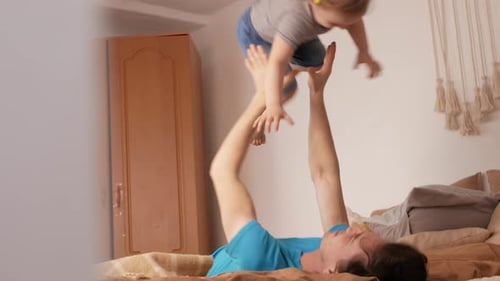 Playful Father Lifts Child on Bed Indoors