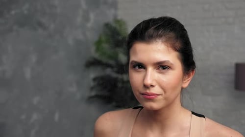 Woman Drinks Water after Exercise and Smiles