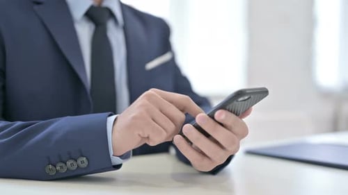 Man in Suit Using Smartphone at Desk
