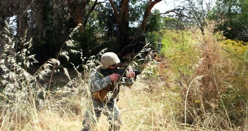 Soldier Crouches and Walks With Rifle in Woods