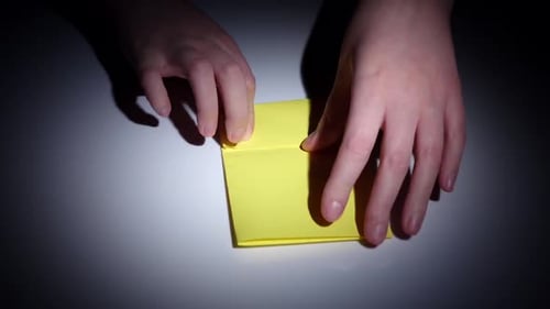 Hands Making Origami With Yellow Paper