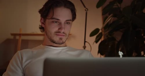 Close Up View of Positive Young Man Using Laptop and Smiling While Sitting on Couch at Home