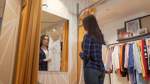Tiro de ângulo baixo de uma bela jovem tentando um vestido na loja de roupas