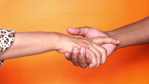Close Up of Couple Holding Hands Against Orange Background.