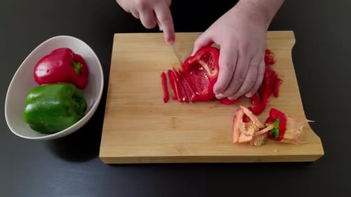 Hand of chef finely slices red pepper. Close up and high angle