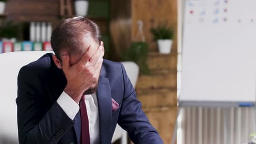 Müder, depressiver und erschöpfter Geschäftsmann allein im Büro
