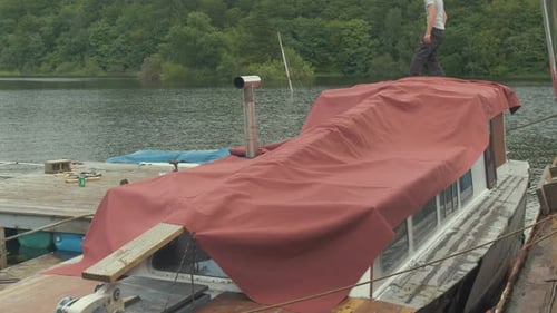Young Adult on Tarp-Covered Boat on Lake
