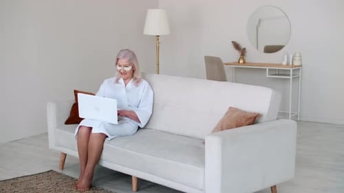 Senior Woman Using Laptop on Sofa at Home