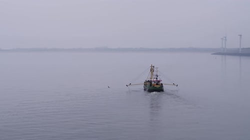 Green fishing boat with outstretched yellow fishermen's arms sails over the calm North Sea with the