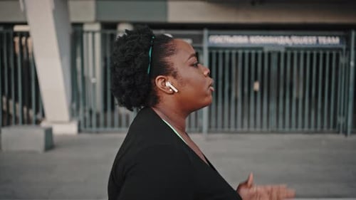 Young Overweight African American Woman Practicing Cardio Training Running Alone in Urban Area