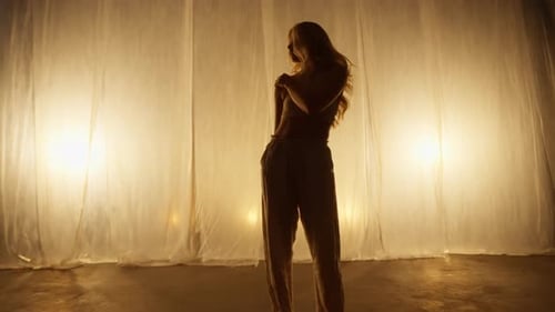 Silhouette of a Professional Dancer Performing in Studio in Soft Warm Lighting