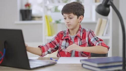 Boy Attends Online Class and Writes on Paper