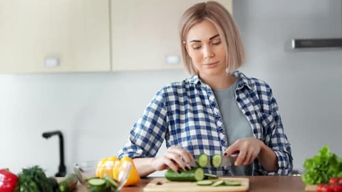 Woman Slicing Cucumber in Kitchen for Healthy Meal