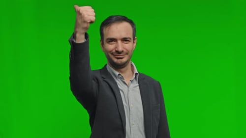 Young Happy Businessman Shows Thumb Up on Green Background in Studio