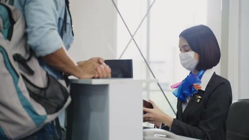 Airline Agent Checks Passenger's Passport at Airport Counter
