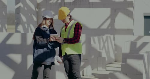 Young Engineer and Contractor Discussing Over Digital Tablet
