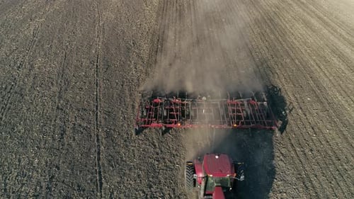 Tillage, Farm Tractor with Plow Cultivates Soil on Field Before Seeding Agricultural Crops