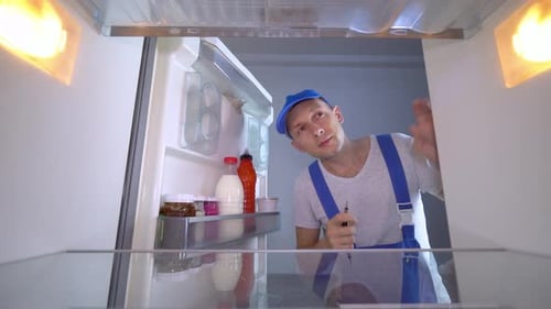 Repair Man Working Inside a Refrigerator