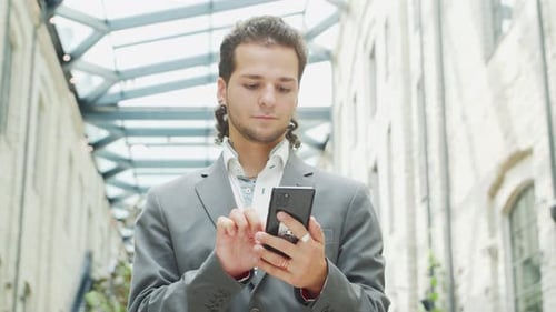 Young Adult Uses Smartphone in Sunlit Urban Office