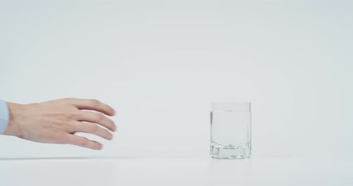 Hand takes glass of water on white background