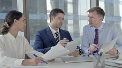 Geschäftsmann mittleren Alters, der mit seinen Assistenten Argumente zu Dokumenten hat