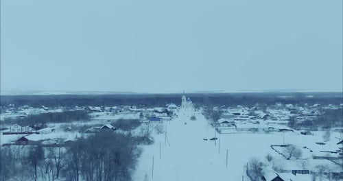 Copter Flies Over the Village in Winter the Roofs of Houses Trees and the Church are Covered with