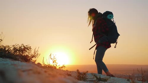 Woman Hiking Up a Hillside at Sunset