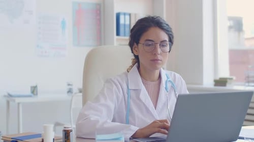Female Doctor Using Laptop in Bright Office