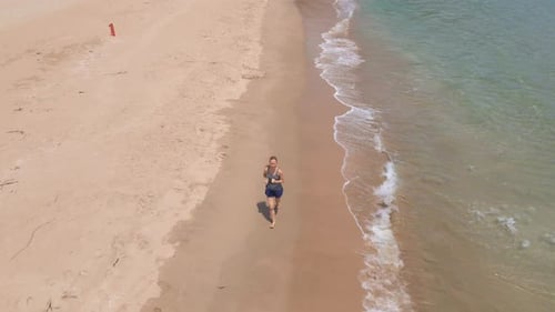 Aerial Shot of a Young Woman Running on a Beautiful Beach. Concept of Healthy Lifestyle and Sports