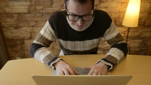 Man Typing on Laptop at Table Indoors