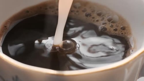 Pouring Fresh Milk into a Cup of Coffee