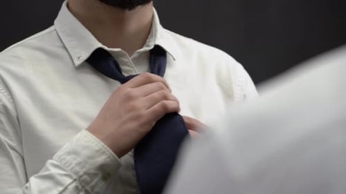 Man tying a tie. Reflect on mirror.