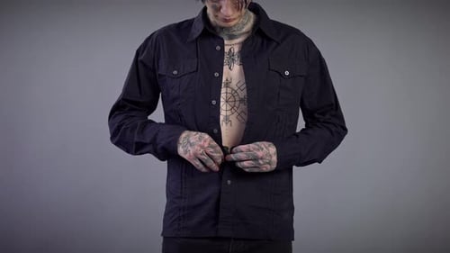 Front View Unrecognizable Young Man with Tattooed Torso and Hands Buttoning Shirt