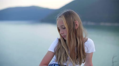 Nachdenkliches Teenager-Mädchen sitzt und schaut auf Sea Coast